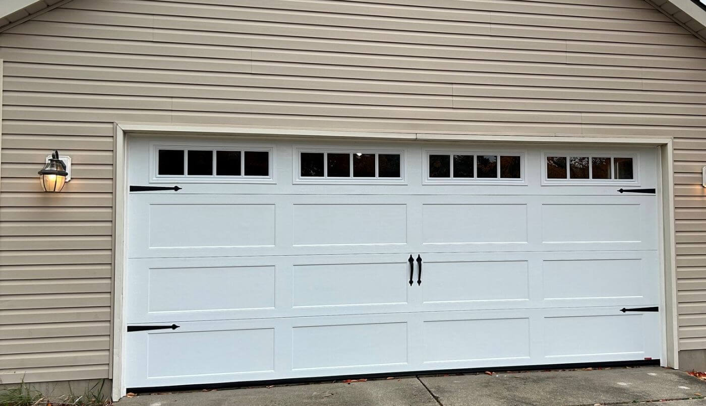 A garage door illuminated by lights on either side, creating a welcoming and secure entrance to the home.